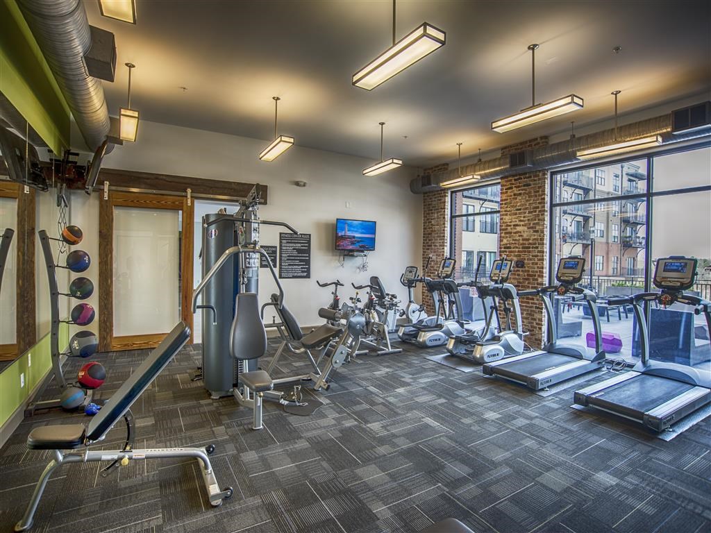 a gym with weights and cardio machines and a window