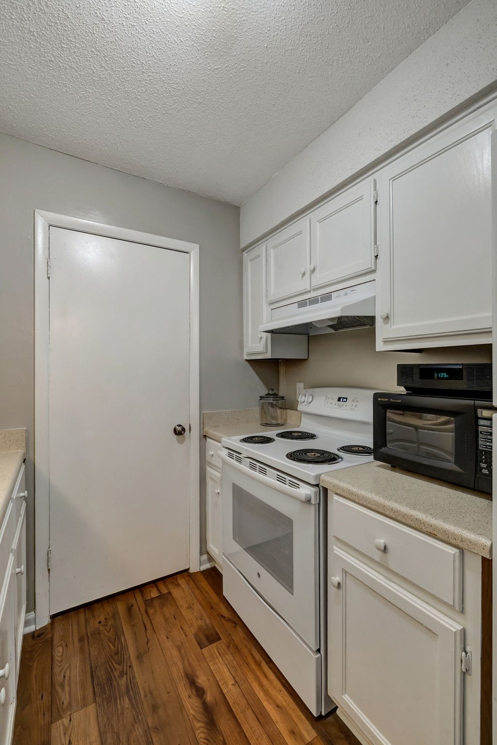 a kitchen with white cabinets and appliances and a white door