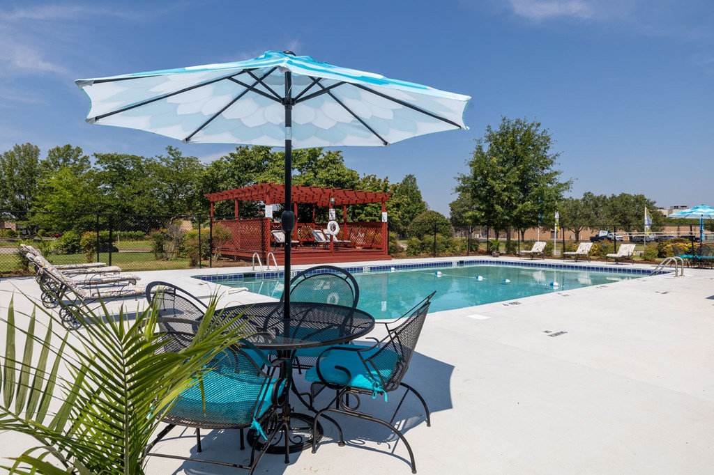 a swimming pool with a table and chairs under an umbrella