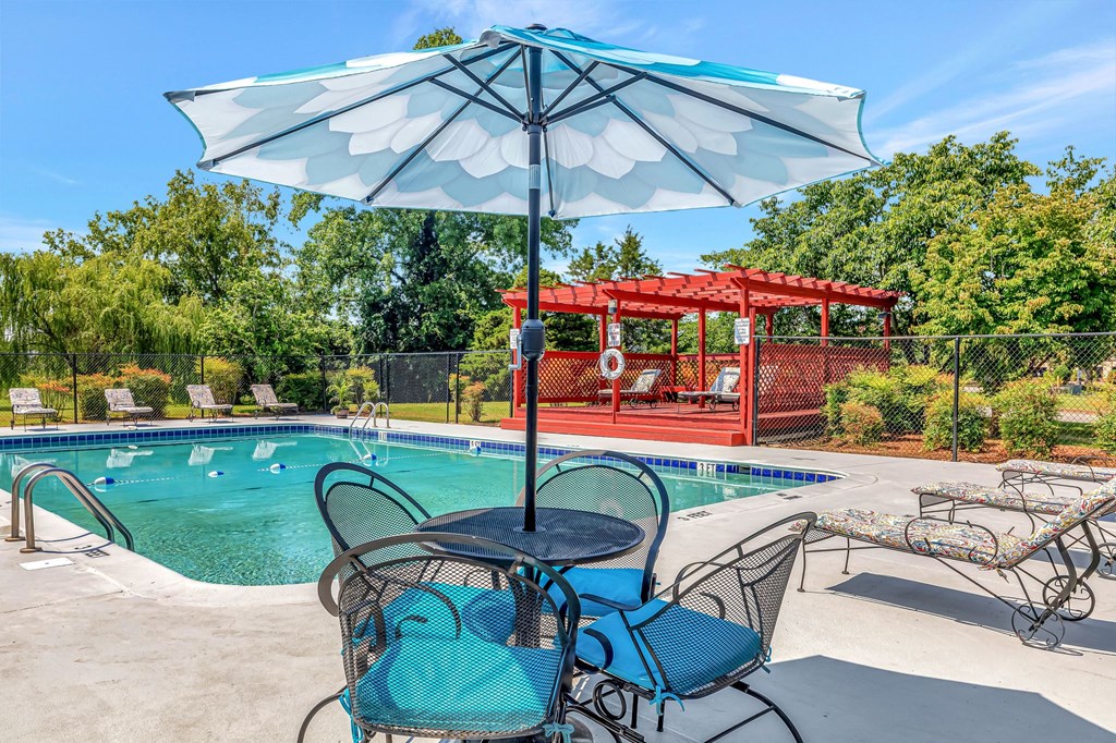 our apartments have a pool and patio with chairs and an umbrella
