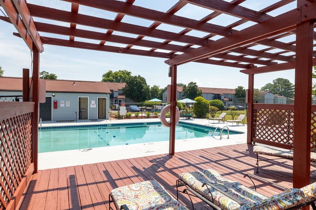 a swimming pool with a wooden deck with chairs