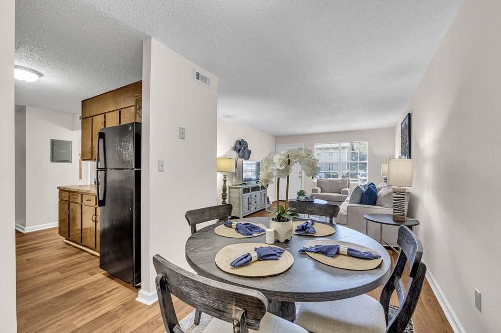 a dining room table with chairs and a living room with a refrigerator
