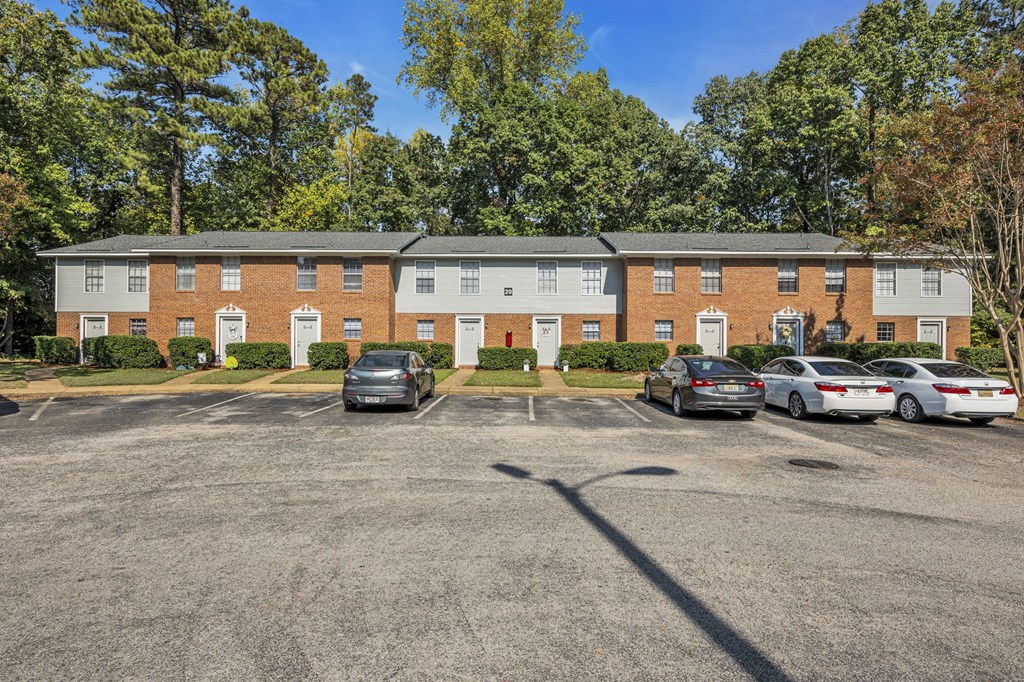 an empty parking lot in front of a brick apartment building