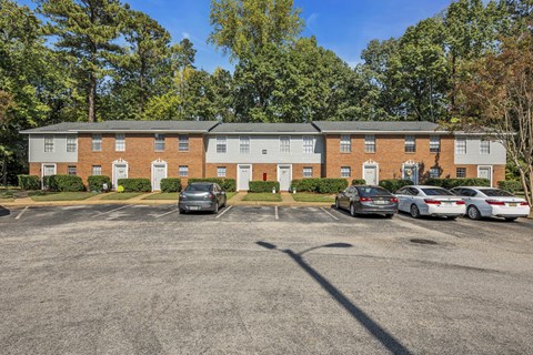 an empty parking lot in front of a brick apartment building