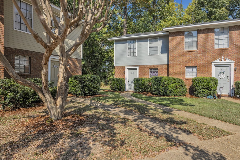 a brick building with white doors and a tree in front