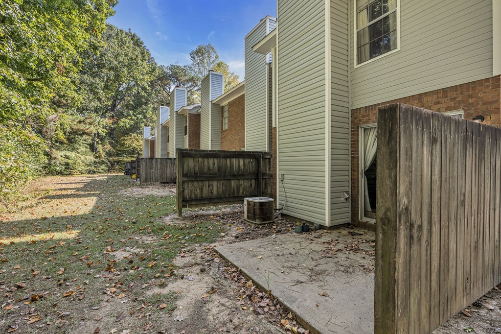 the back yard of a house with a wooden fence and a dirt path