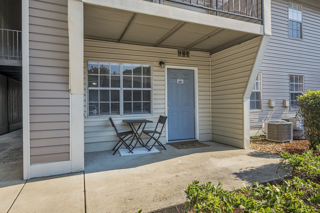 a patio with two chairs and a table in front of a blue door