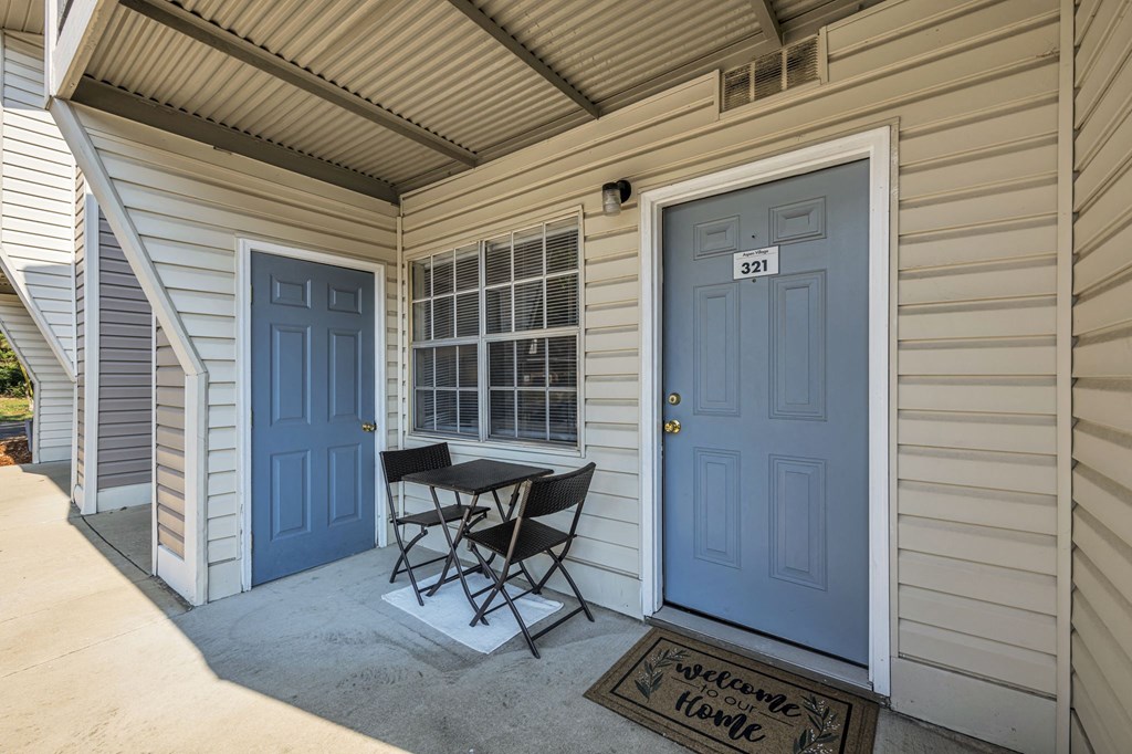 a patio with a table and chairs in front of a blue door