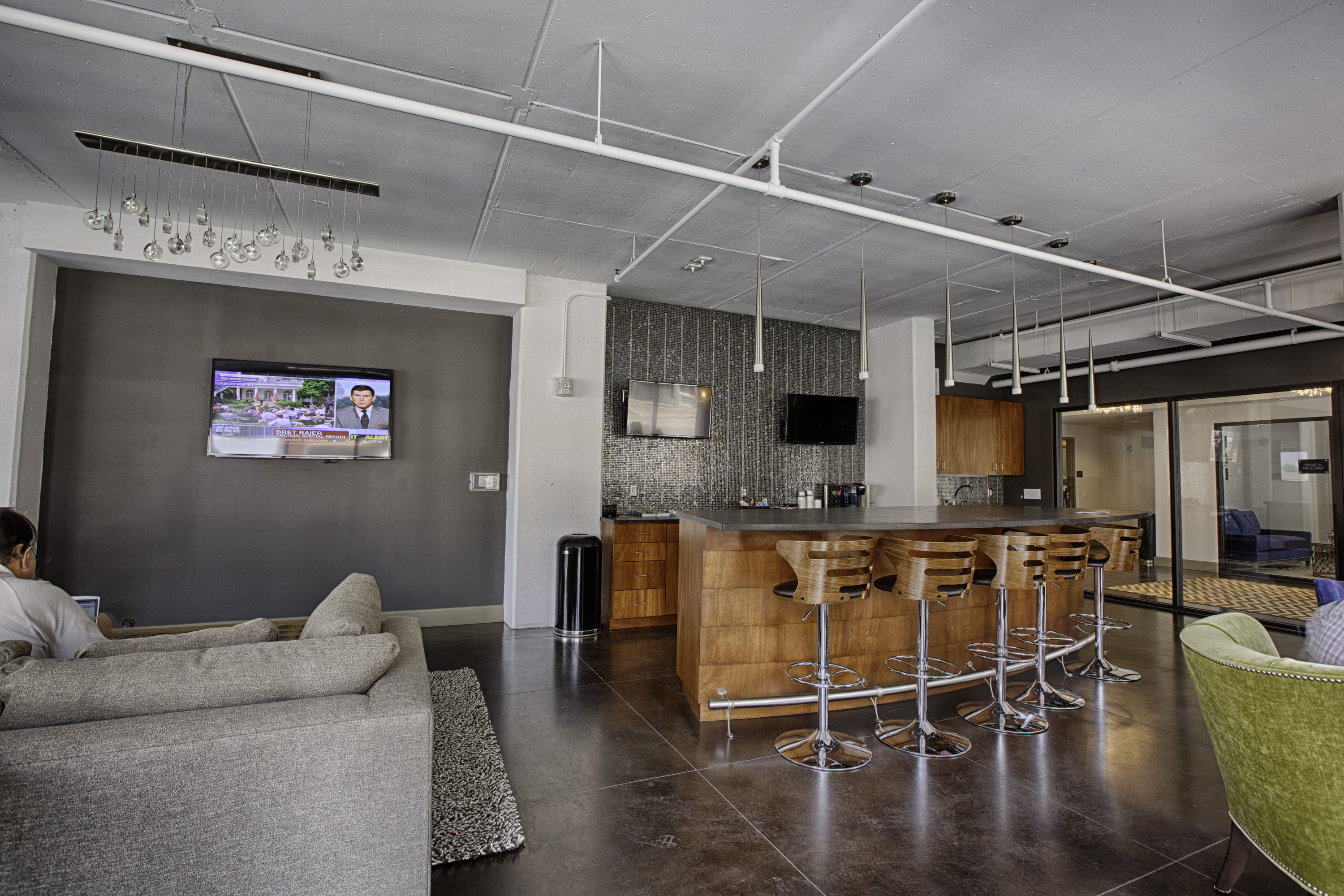 a living room with a bar and a kitchen with stools