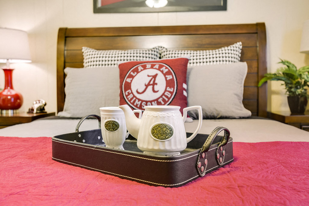 a tray with two cups and a coffee mug sitting on a bed