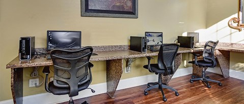 a home office with three computers on a long desk