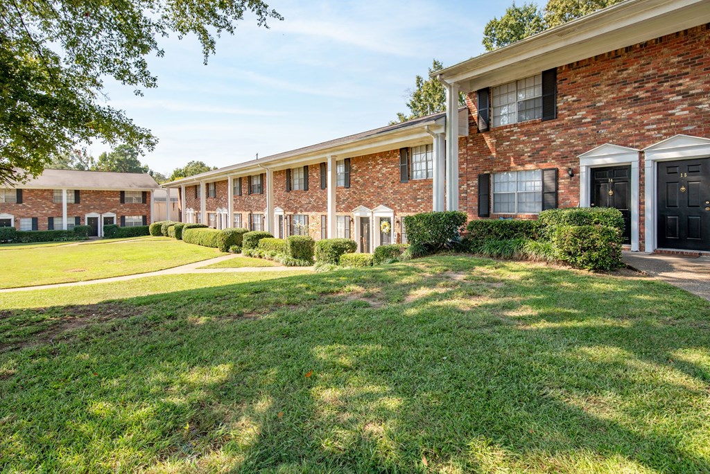 exterior view of a brick apartment building with grass and trees