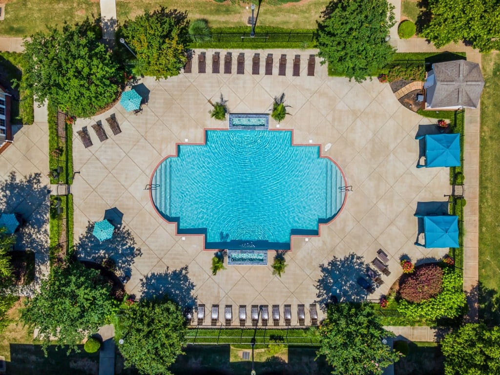 an aerial view of a swimming pool in the center of a city with trees