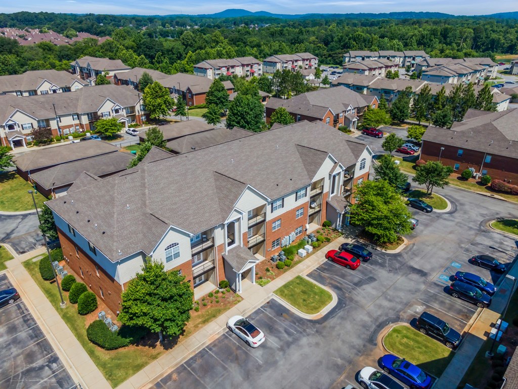 an aerial view of a building with cars parked in a parking lot