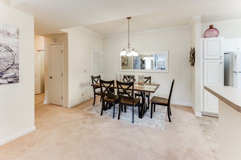 a dining room with a table and chairs and a kitchen with a refrigerator