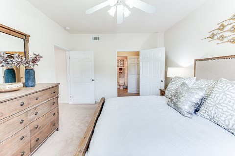 a bedroom with a bed and a dresser and a ceiling fan
