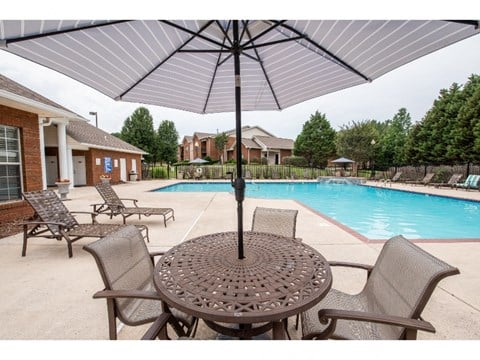our apartments have a pool and a patio with chairs and an umbrella