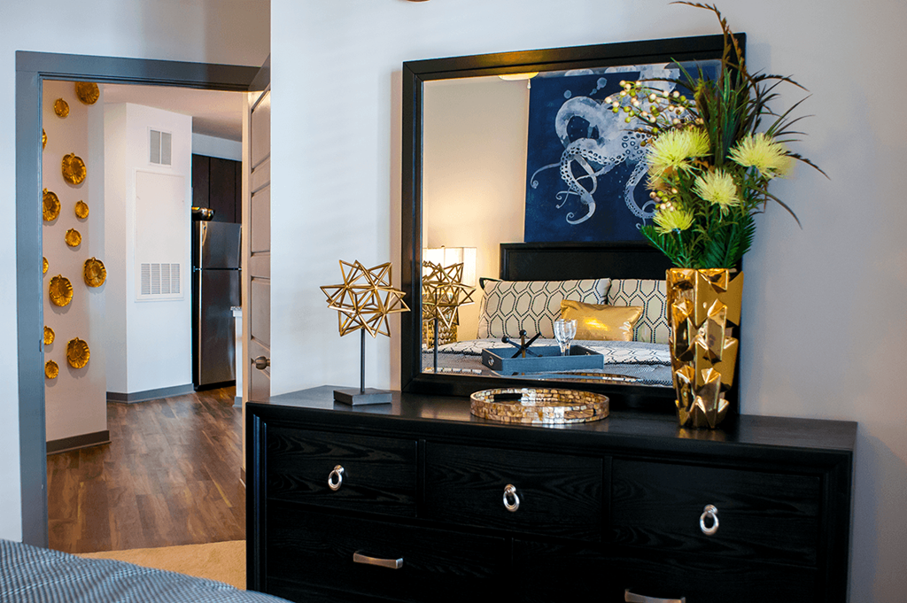 a bedroom with a black dresser with a large mirror and a bed
