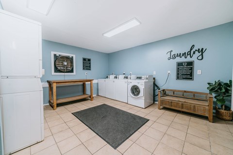 A laundry room with a washer and dryer, a bench, and a fan.