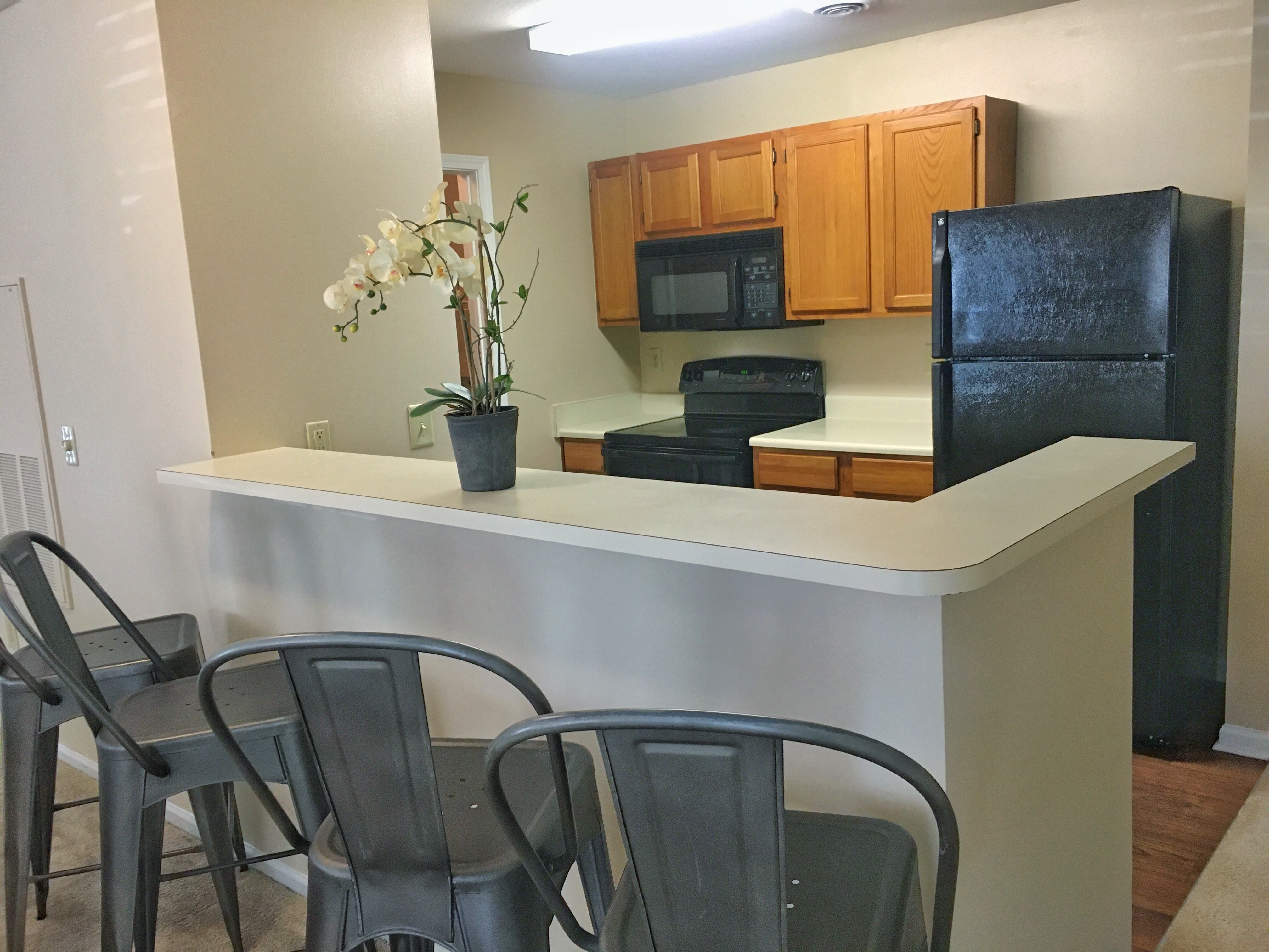 a kitchen with a counter and chairs and a refrigerator