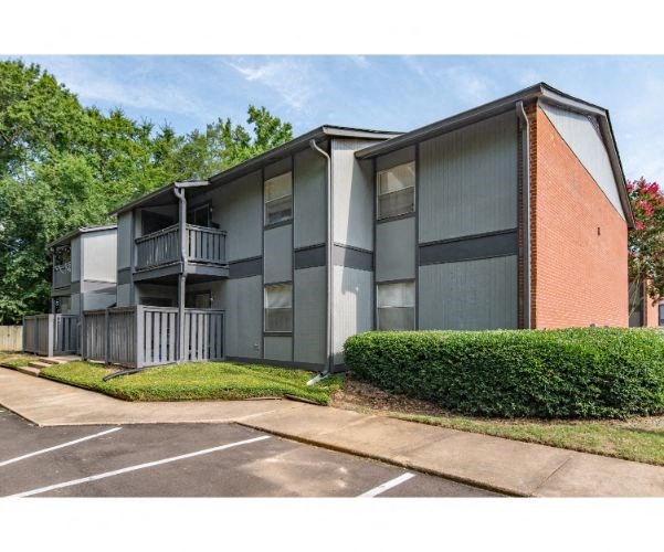 an apartment building with a parking lot and trees