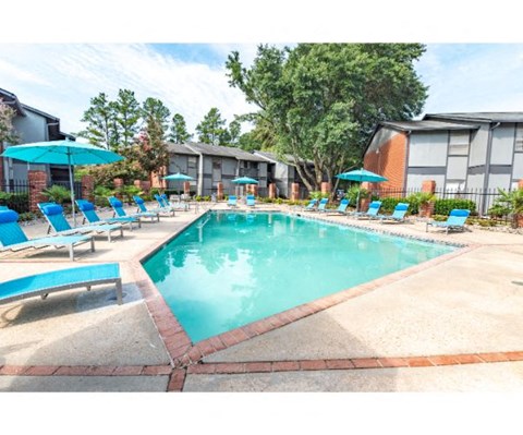 a resort style pool with blue chairs and umbrellas