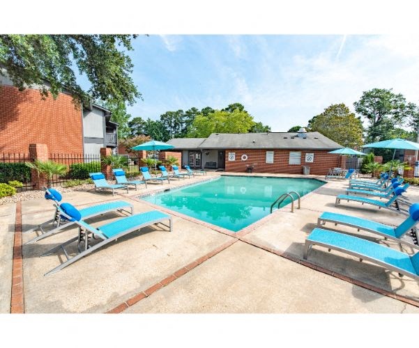 a resort style pool with blue chairs and umbrellas