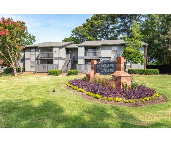 an image of an apartment building with a yard and a sign