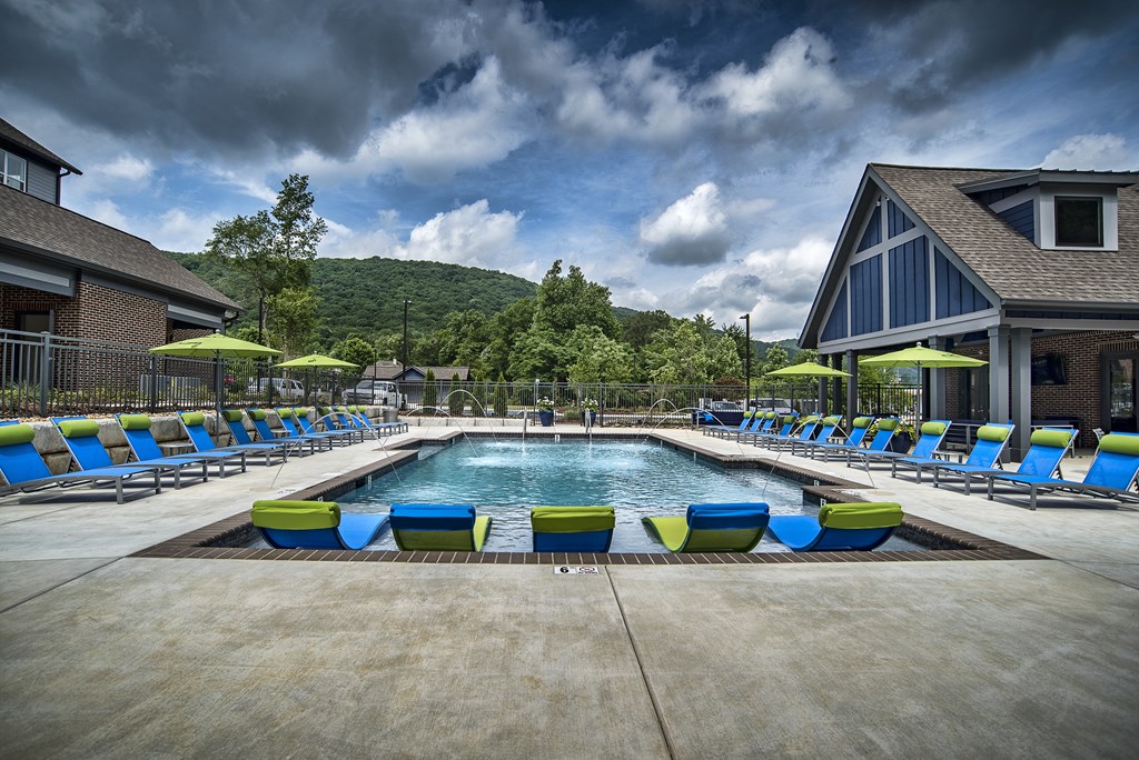 a swimming pool with blue and yellow lounge chairs around it