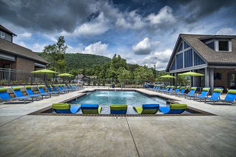 a swimming pool with blue and yellow lounge chairs around it