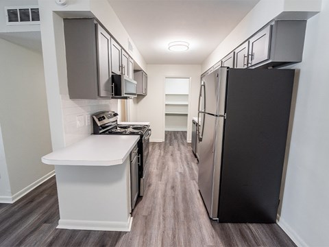 A kitchen with a black refrigerator and white countertops.