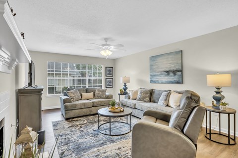 A living room with a grey couch, a coffee table, and a painting on the wall.