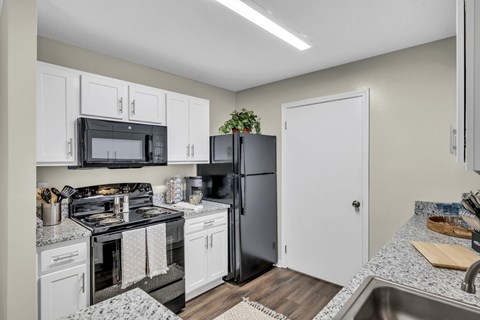 A kitchen with a black stove top oven and a black refrigerator.