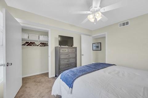 A bedroom with a bed, dresser, and television.