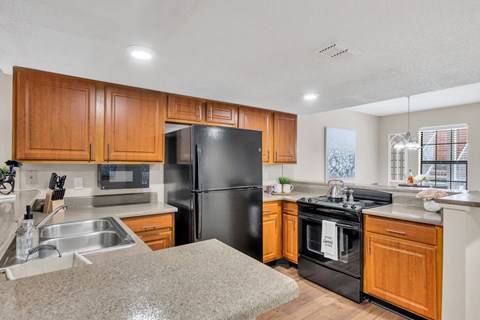 A kitchen with wooden cabinets and a black refrigerator.