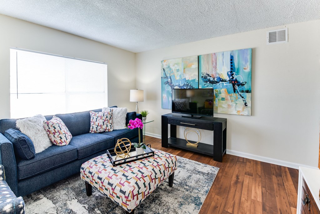a living room with a blue couch and a tv on a stand in front of a window