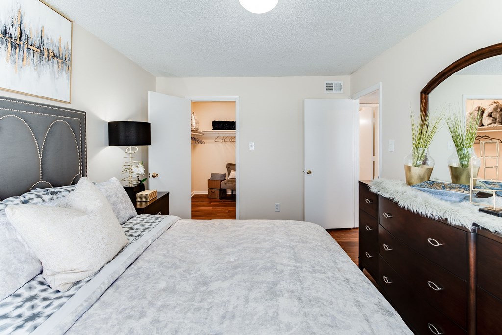 a bedroom with a large bed and a dresser with a mirror