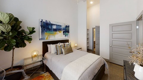A bedroom with a large bed and a painting on the wall.