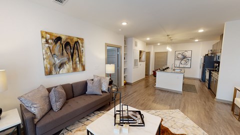A living room with a brown couch and a painting on the wall.