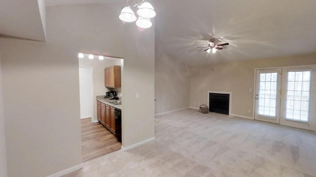 an empty living room and kitchen with a ceiling fan