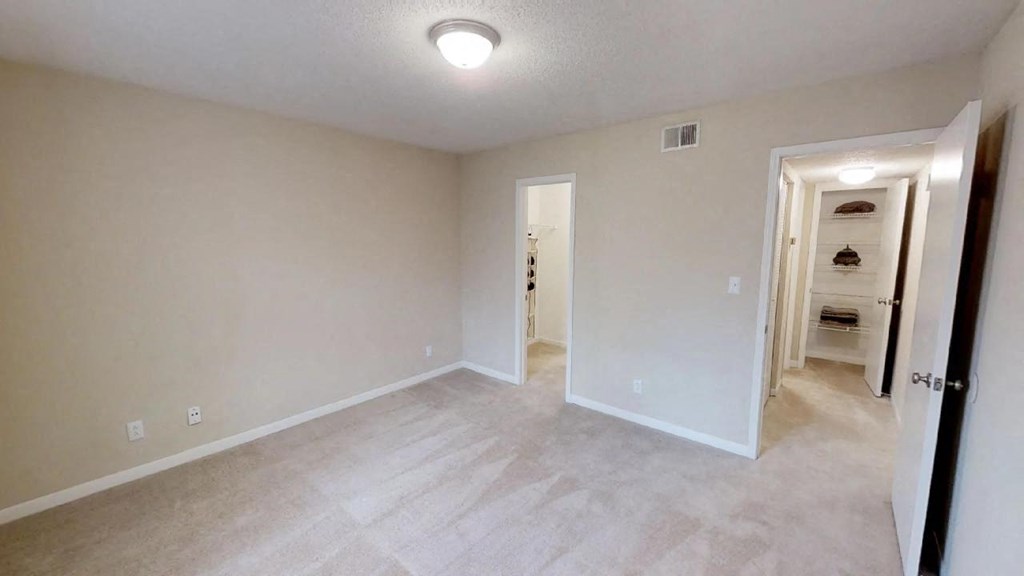 an empty living room with a hallway to a bedroom and a closet