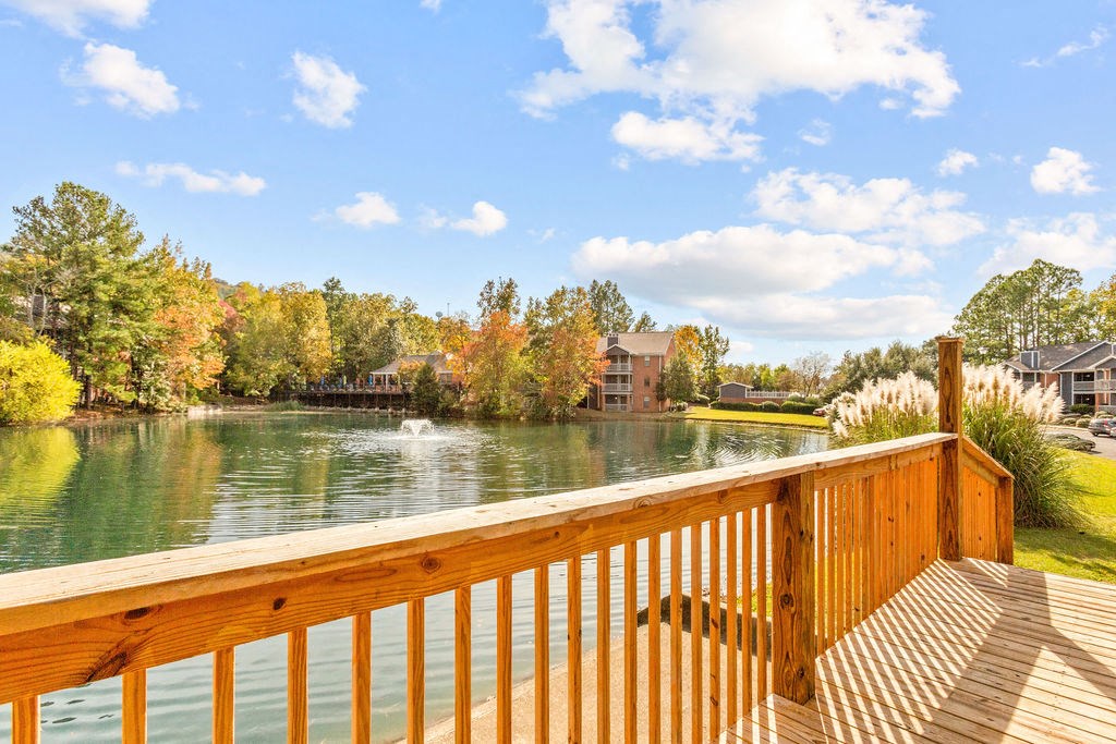 a view of a lake from a deck with a wooden railing