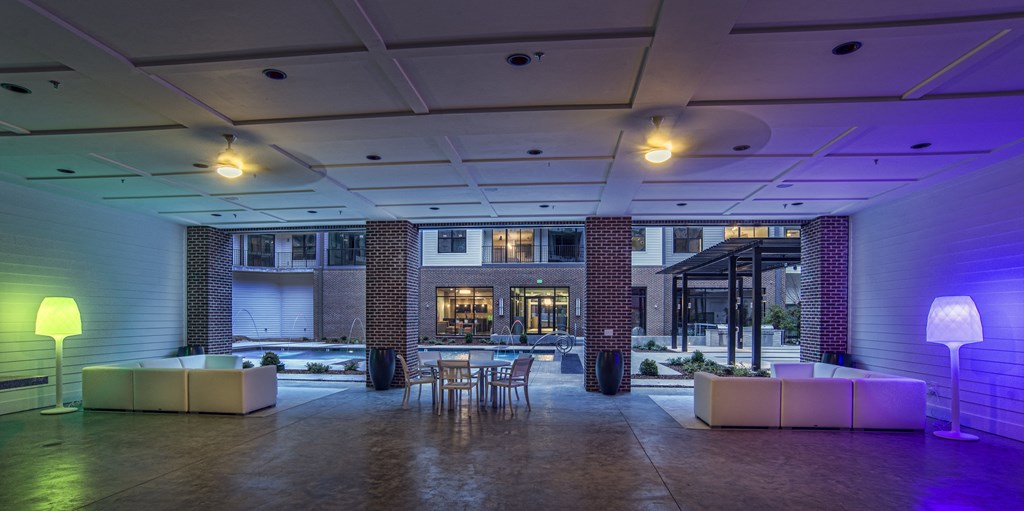 the lobby of a building with tables and chairs and purple lighting
