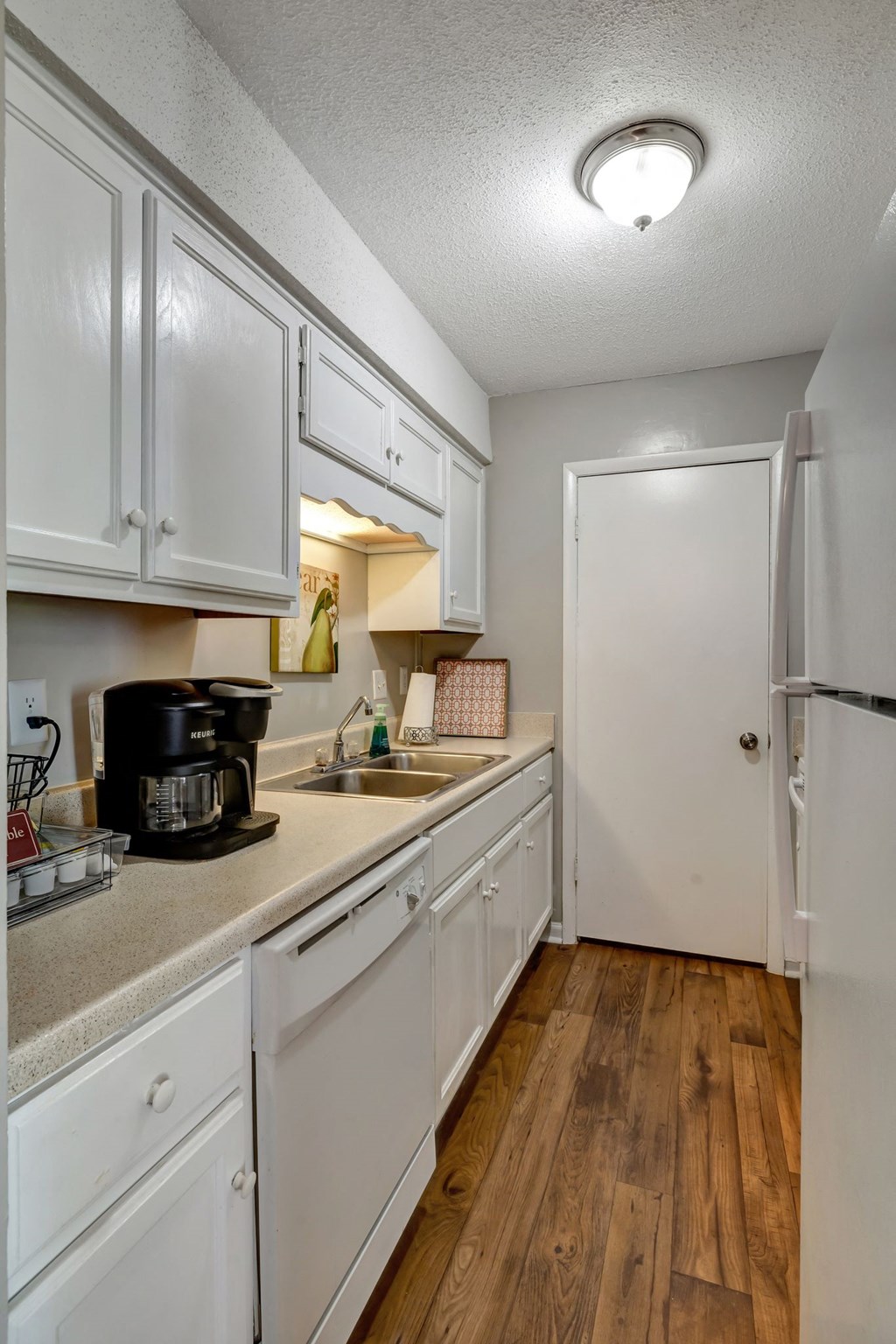 a kitchen with white cabinets and a sink and a refrigerator