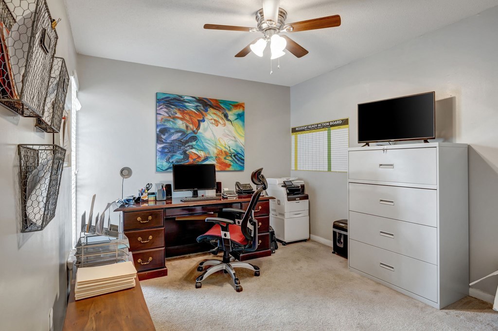 a home office with a desk and a tv