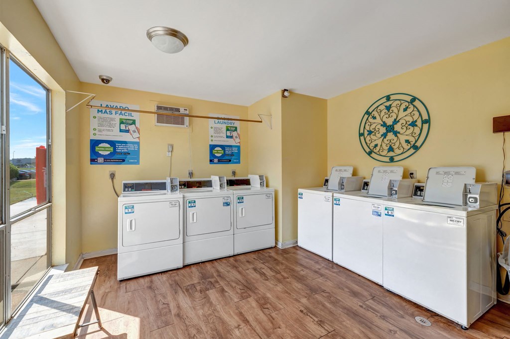 a laundry room with four washers and dryers and a window and a door