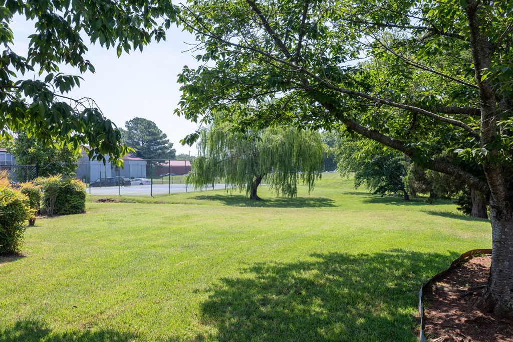 a park with trees and grass and a tennis court