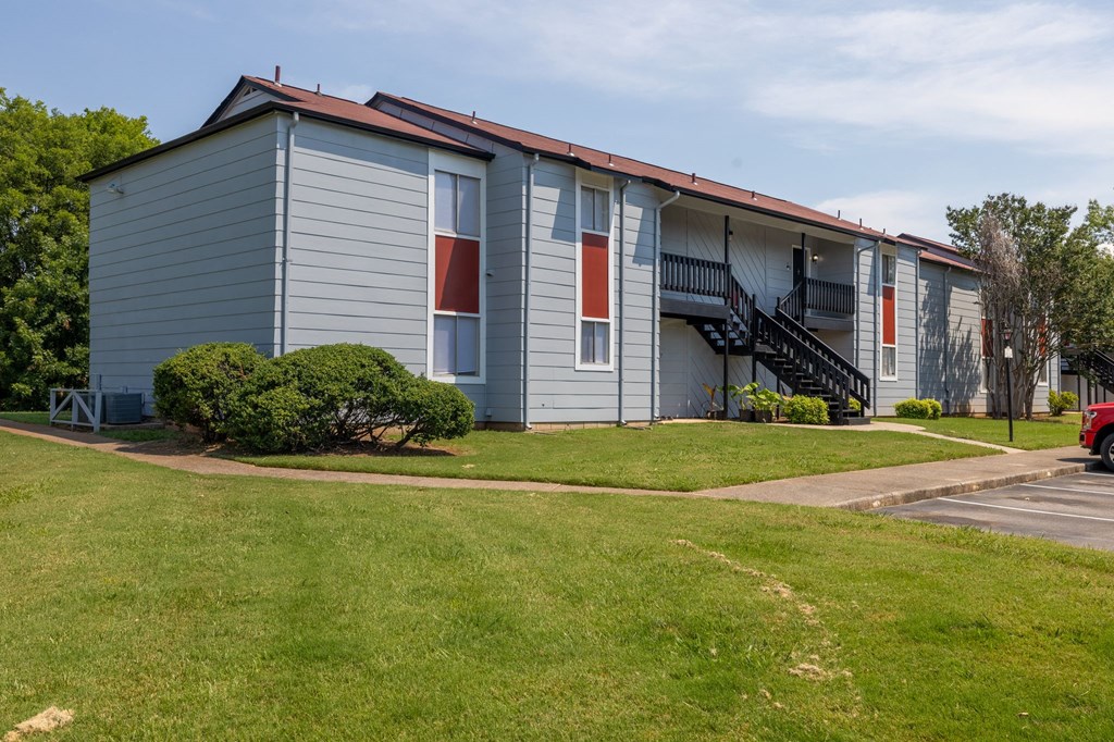 a blue building with red and white doors and a lawn