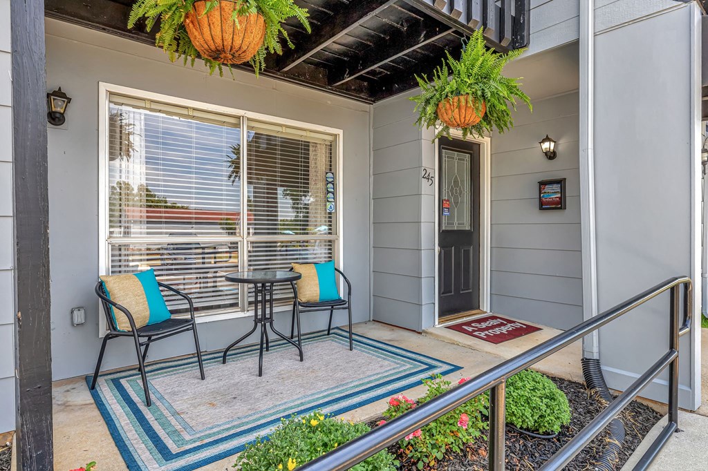 a porch with two chairs and a table and a door