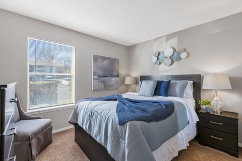 A bedroom with a large bed and a window overlooking a parking lot.